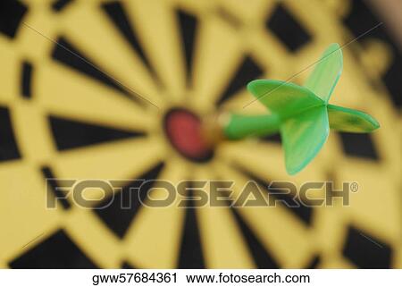 Stock Image - Close-up of a dart on the bull's-eye on a dartboard. Fotosearch