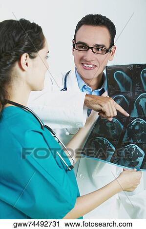 Close-up of a female doctor holding an X-Ray with a male doctor pointing at it View Large Photo Image Stock Image - Close-up of a female doctor holding an X-Ray with a male doctor pointing at it. Fotosearch