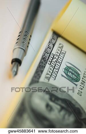 Stock Image - Close-up of a fountain pen and one hundred dollar bill. Fotosearch