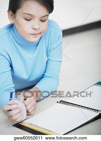 Close-up of a girl holding a pen and looking at a spiral notebook View Large Photo Image Stock Image - Close-up of a girl holding a pen and looking at a spiral notebook. Fotosearch