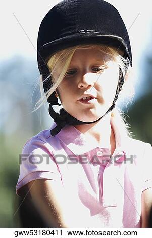 Stock Image - Close-up of a girl with a riding hat on her head. Fotosearch