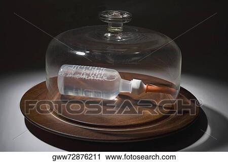 Close-up of a glass container covering a bottle on a dish View Large Photo Image Stock Image - Close-up of a glass container covering a bottle on a dish. Fotosearch