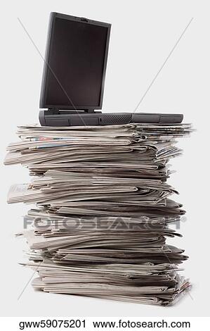 Stock Image - Close-up of a laptop on a stack of newspapers. Fotosearch