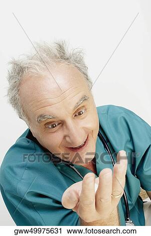 Close-up of a male doctor looking at his hand and smiling View Large Photo Image Stock Image - Close-up of a male doctor looking at his hand and smiling. Fotosearch