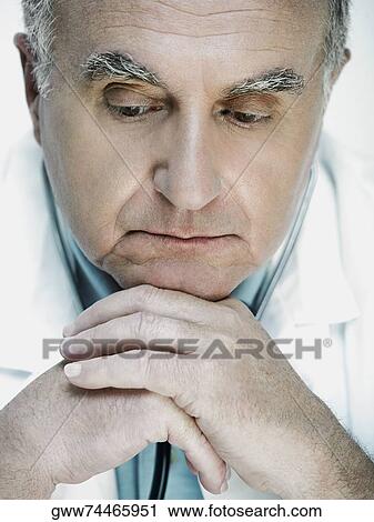 Stock Image - Close-up of a male doctor resting his chin on his hands. Fotosearch