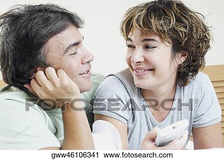 Close-up of a mature woman holding a remote control with a mature man looking at her View Large Photo Image Stock Image - Close-up of a mature woman holding a remote control with a mature man looking at her. Fotosearch