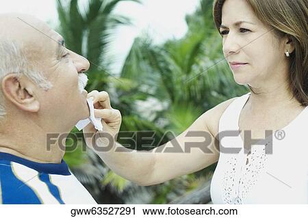 Close-up of a mature woman wiping a mature man's chin View Large Photo Image Stock Image - Close-up of a mature woman wiping a mature man's chin. Fotosearch