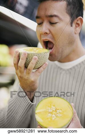 Close-up of a mid adult man eating a cantaloupe View Large Photo Image Stock Image - Close-up of a mid adult man eating a cantaloupe. Fotosearch