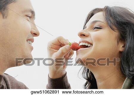 Close-up of a mid adult man feeding a young woman View Large Photo Image Stock Image - Close-up of a mid adult man feeding a young woman. Fotosearch