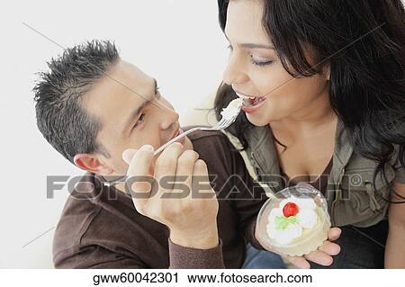 Close-up of a mid adult man feeding a young woman View Large Photo Image Stock Image - Close-up of a mid adult man feeding a young woman. Fotosearch