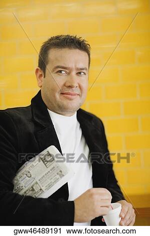 Stock Image - Close-up of a mid adult man holding a disposable cup. Fotosearch