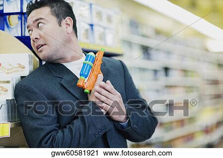Stock Image - Close-up of a mid adult man holding a squirt gun. Fotosearch