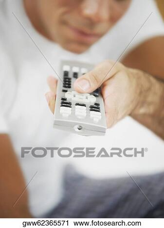 Stock Image - Close-up of a mid adult man holding a remote control. Fotosearch