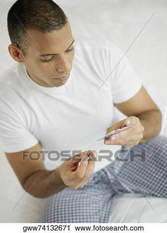 Close-up of a mid adult man holding a pill and a blister pack View Large Photo Image Stock Image - Close-up of a mid adult man holding a pill and a blister pack. Fotosearch