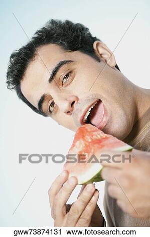 Close-up of a mid adult man holding watermelon slice with his mouth open View Large Photo Image Stock Image - Close-up of a mid adult man holding watermelon slice with his mouth open. Fotosearch