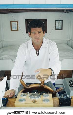 Stock Image - Close-up of a mid adult man holding the helm of a motorboat. Fotosearch