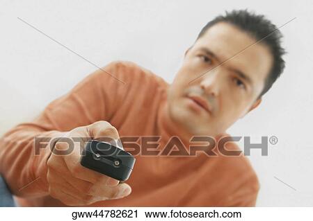 Stock Image - Close-up of a mid adult man operating a remote control. Fotosearch