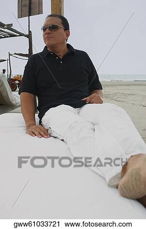 Close-up of a mid adult man reclining on the bed View Large Photo Image Stock Image - Close-up of a mid adult man reclining on the bed. Fotosearch