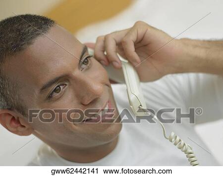 Close-up of a mid adult man talking on the telephone and smiling View Large Photo Image Stock Image - Close-up of a mid adult man talking on the telephone and smiling. Fotosearch
