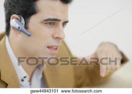 Close-up of a mid adult man wearing a hands free device View Large Photo Image Stock Image - Close-up of a mid adult man wearing a hands free device. Fotosearch