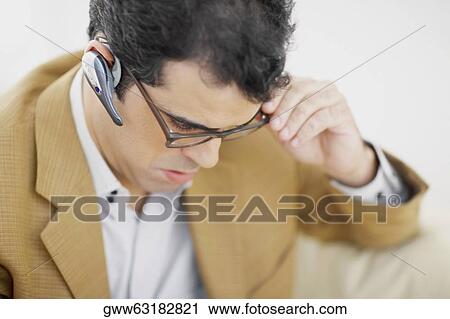 Close-up of a mid adult man wearing a hands free device View Large Photo Image Stock Image - Close-up of a mid adult man wearing a hands free device. Fotosearch