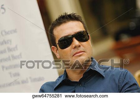 Close-up of a mid adult man wearing sunglasses View Large Photo Image Stock Image - Close-up of a mid adult man wearing sunglasses. Fotosearch
