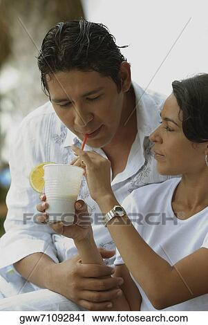 Close-up of a mid adult woman feeding a glass of juice to a mid adult man View Large Photo Image Stock Image - Close-up of a mid adult woman feeding a glass of juice to a mid adult man. Fotosearch