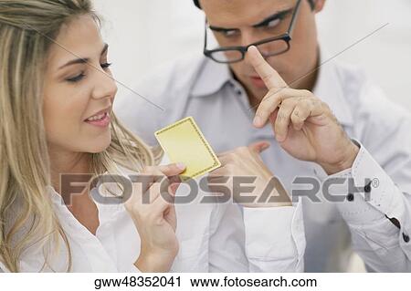 Close-up of a mid adult woman holding a credit card with a mid adult man looking at her View Large Photo Image Stock Image - Close-up of a mid adult woman holding a credit card with a mid adult man looking at her. Fotosearch
