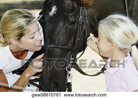 Close-up of a mid adult woman with her daughter touching a horse View Large Photo Image Stock Image - Close-up of a mid adult woman with her daughter touching a horse. Fotosearch