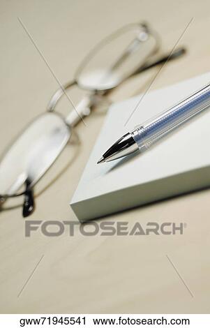 Stock Image - Close-up of a pair of eyeglasses with a pen and adhesive notes. Fotosearch