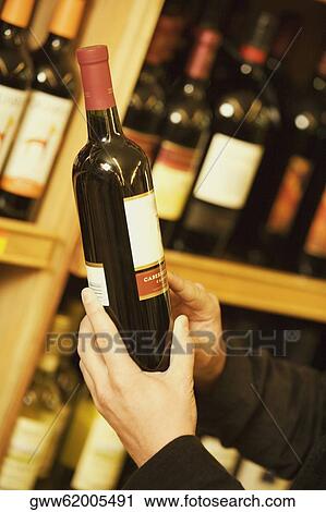 Close-up of a person's hand holding a wine bottle in a liquor store View Large Photo Image Stock Image - Close-up of a person's hand holding a wine bottle in a liquor store. Fotosearch