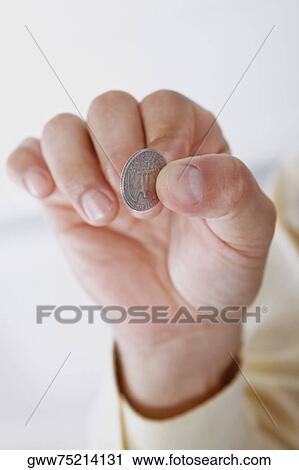 Stock Image - Close-up of a person's hand holding a coin. Fotosearch