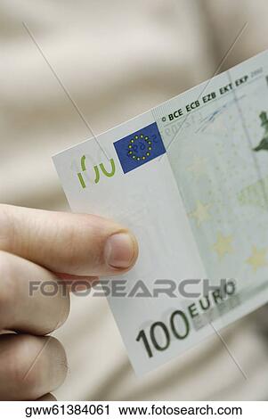 Close-up of a person's hand holding one hundred Euro banknote View Large Photo Image Stock Image - Close-up of a person's hand holding one hundred Euro banknote. Fotosearch