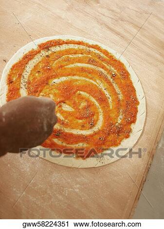 Close-up of a person's hand sprinkling oregano on pizza base View Large Photo Image Stock Image - Close-up of a person's hand sprinkling oregano on pizza base. Fotosearch