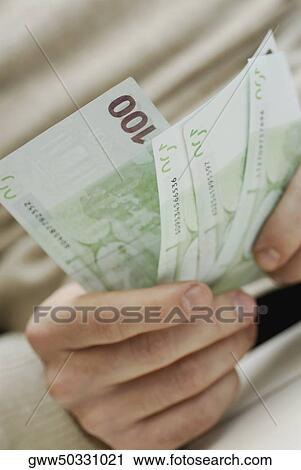 Close-up of a person's hands holding three one hundred Euro banknotes View Large Photo Image Stock Image - Close-up of a person's hands holding three one hundred Euro banknotes. Fotosearch