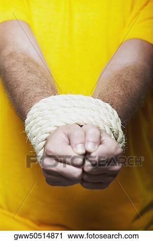 Stock Image - Close-up of a person's hands tied together with a rope. Fotosearch