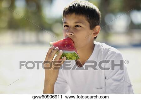 Stock Image - Close-up of a teenage boy eating a slice of watermelon. Fotosearch