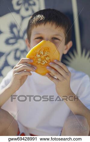 Close-up of a teenage boy holding a slice of melon View Large Photo Image Stock Image - Close-up of a teenage boy holding a slice of melon. Fotosearch
