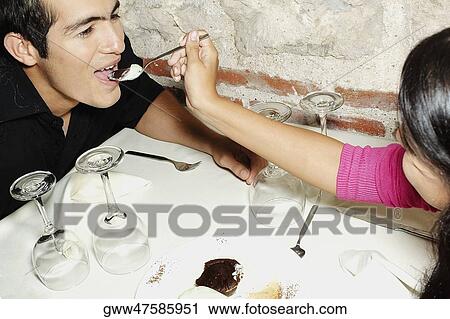 Stock Image - Close-up of a teenage girl feeding a young man. Fotosearch