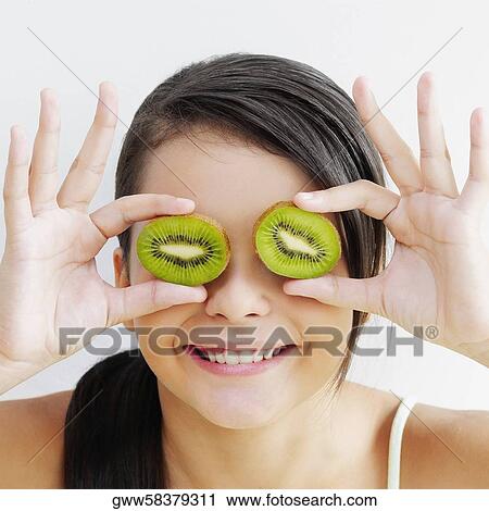 Close-up of a teenage girl holding slices of kiwi fruit in front of her eyes and smiling View Large Photo Image Stock Image - Close-up of a teenage girl holding slices of kiwi fruit in front of her eyes and smiling. Fotosearch