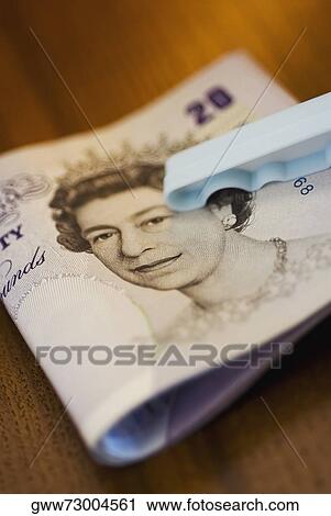 Stock Image - Close-up of a twenty pound bank note with a clothespin. Fotosearch