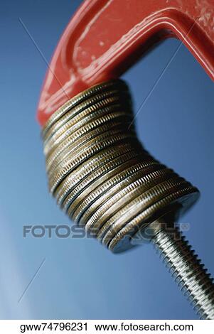 Stock Image - Close-up of a wrench with a stack of coins. Fotosearch