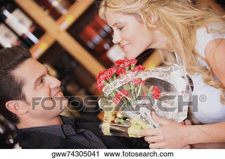 Stock Image - Close-up of a young couple holding a bouquet of flowers and smiling. Fotosearch