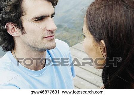 Close-up of a young couple sitting at a pier and looking at each other View Large Photo Image Stock Image - Close-up of a young couple sitting at a pier and looking at each other. Fotosearch