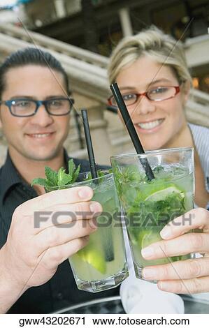 Close-up of a young couple smiling and holding mojito drinks View Large Photo Image Stock Image - Close-up of a young couple smiling and holding mojito drinks. Fotosearch