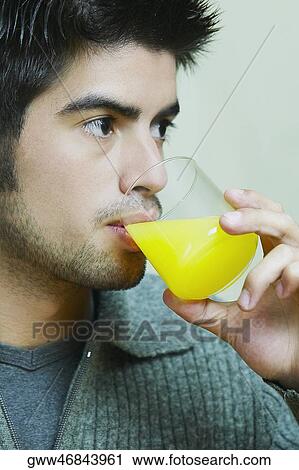Close-up of a young man drinking a glass of orange juice View Large Photo Image Stock Image - Close-up of a young man drinking a glass of orange juice. Fotosearch