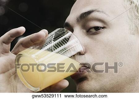 Close-up of a young man drinking a glass of orange juice View Large Photo Image Stock Image - Close-up of a young man drinking a glass of orange juice. Fotosearch