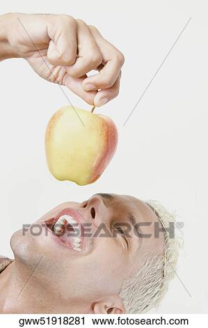 Close-up of a young man holding an apple with his mouth open View Large Photo Image Stock Image - Close-up of a young man holding an apple with his mouth open. Fotosearch