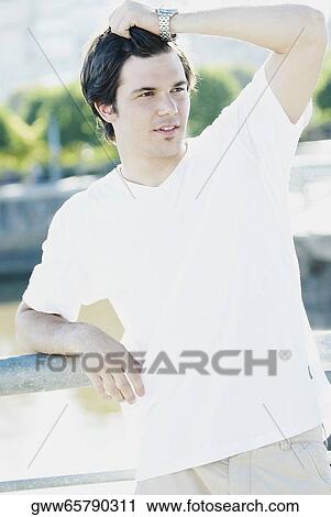 Close-up of a young man leaning against a railing View Large Photo Image Stock Image - Close-up of a young man leaning against a railing. Fotosearch
