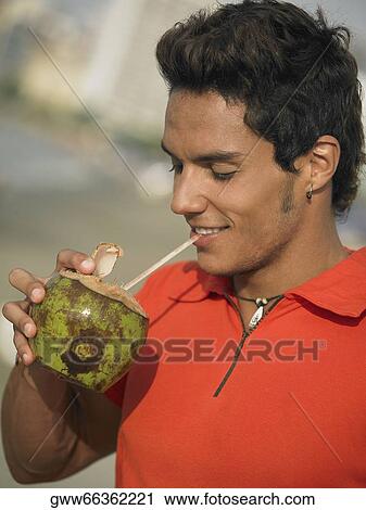 Close-up of a young man sipping juice from a coconut View Large Photo Image Stock Image - Close-up of a young man sipping juice from a coconut. Fotosearch